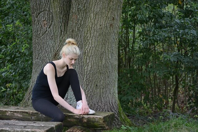 Blondwłosa dziewczyna na ławce w lesie
