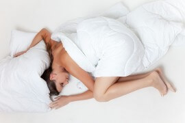 Kobieta śpi w białej pościeli