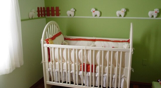 Białe łóżeczko dla dziecka w zielonym pokoju