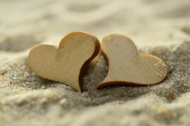 Dwa drewniane serca leżące na plaży