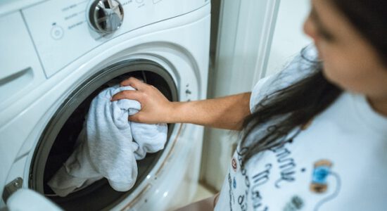 Kobieta wsadza pranie do pralki